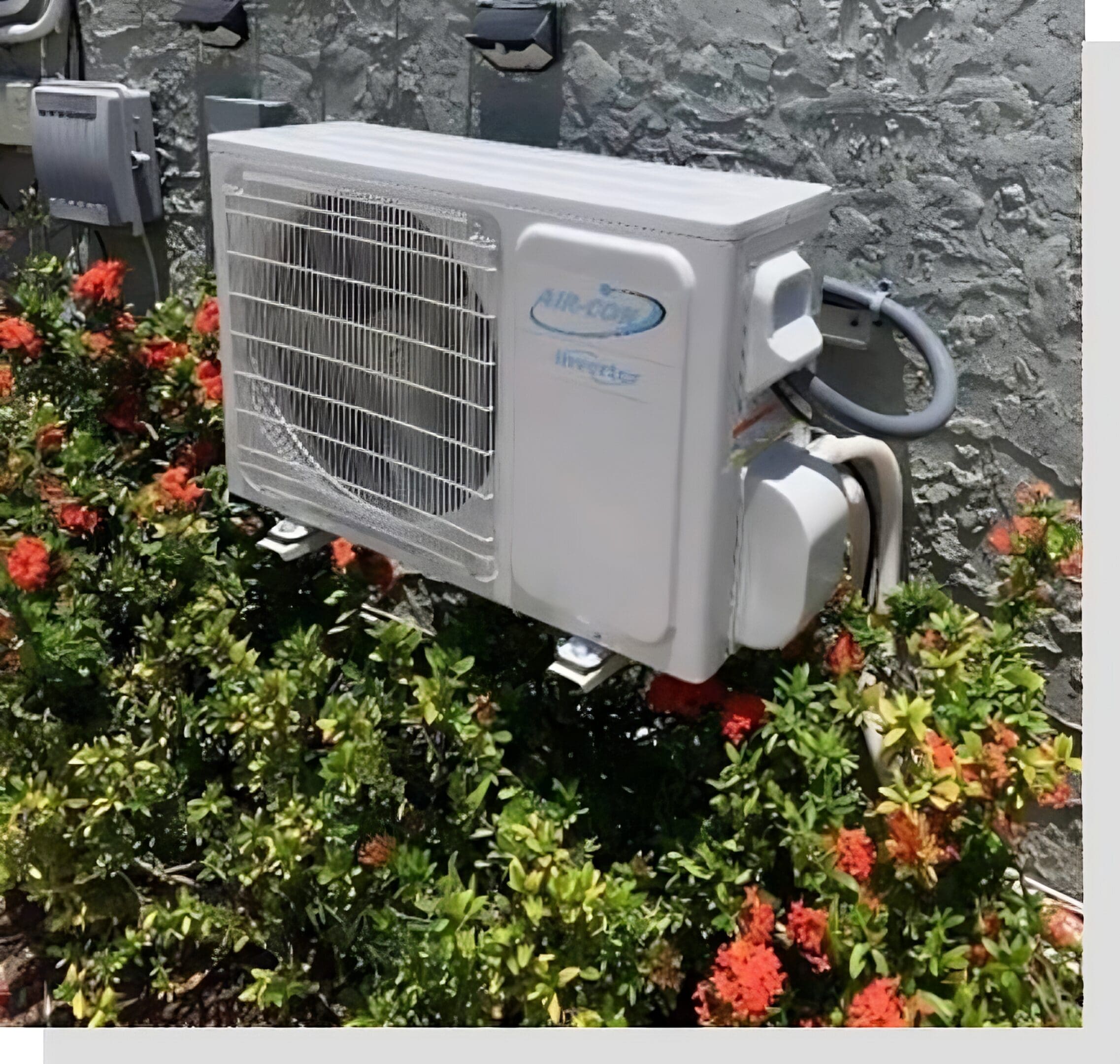 A white air conditioner sitting in the middle of some bushes.