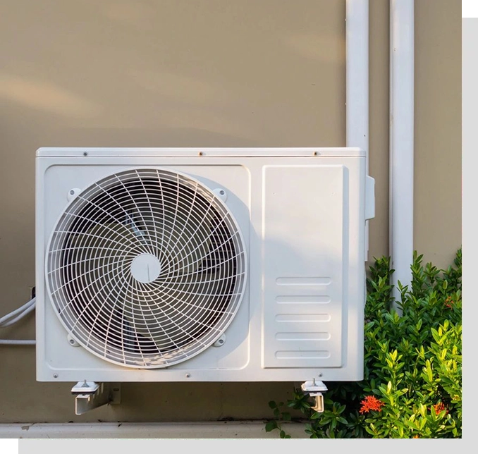 A white air conditioner sitting on top of the ground.