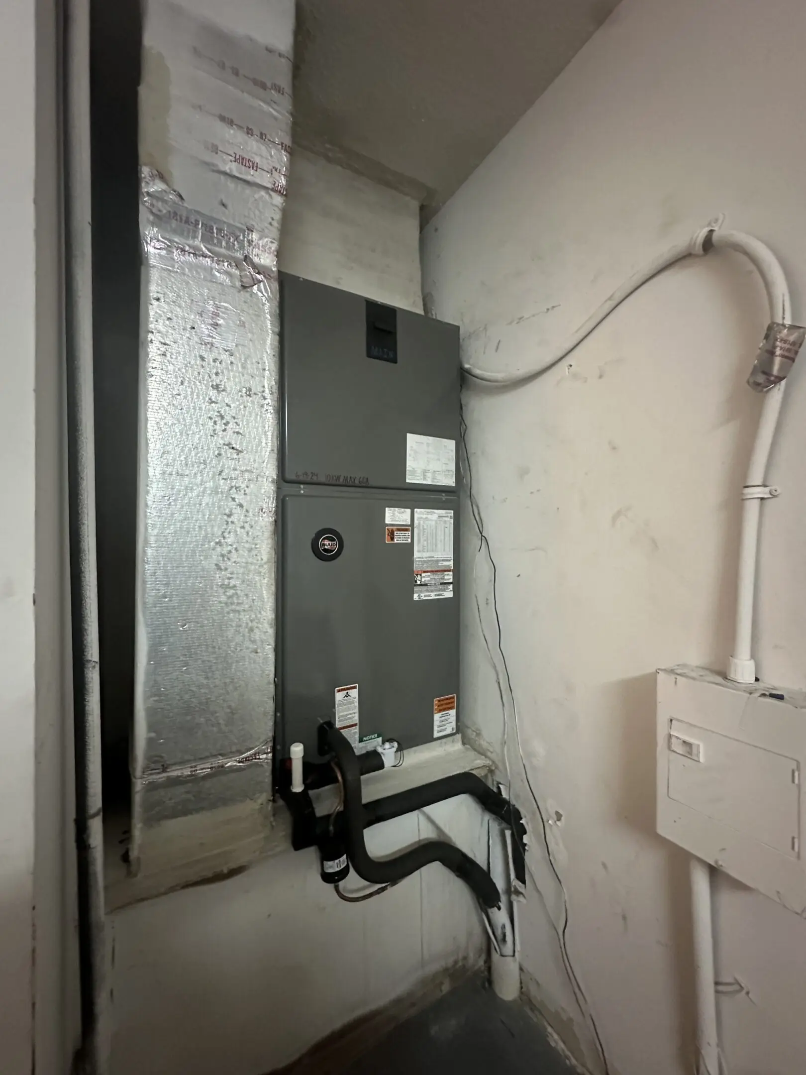 A room with a large air handler and an electrical box.